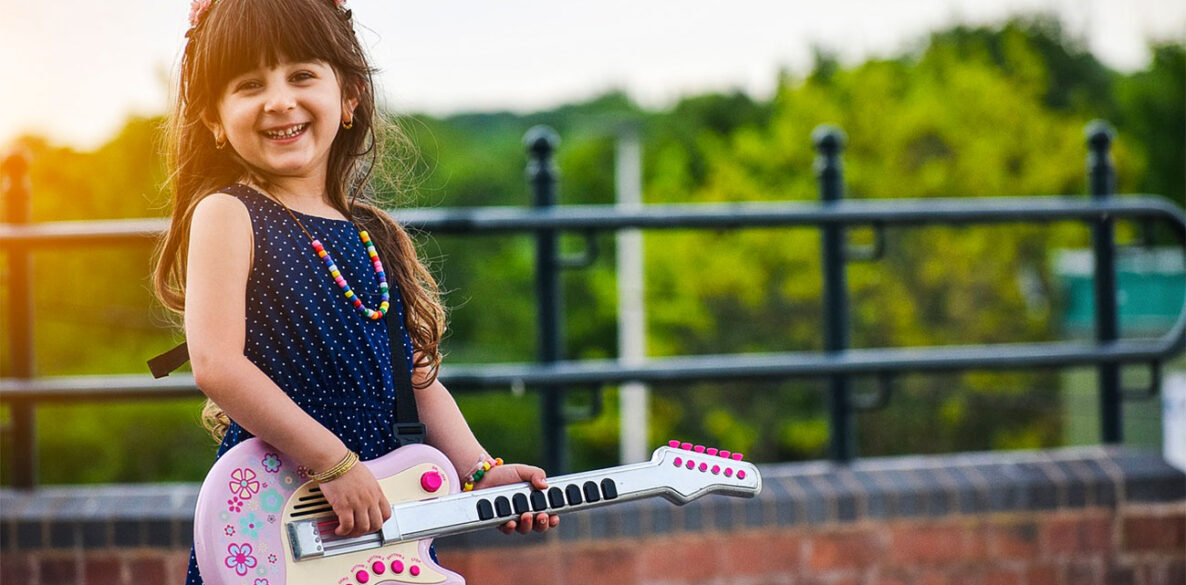 Une petite fille avec sa guitare jouet rose